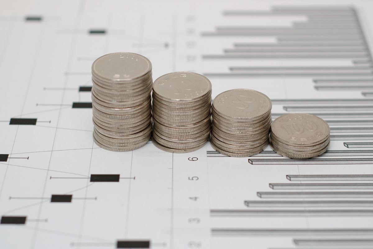 Stacks of silver coins on line graphs and bar charts, illustrating financial growth or investment analysis.